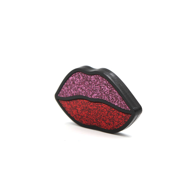 Barrette bouche en acrylique découpe laser, le contour est noir, la lèvre supérieur est rose pailletée et l'inférieur rouge pailleté, vu de trois quart sur fond blanc