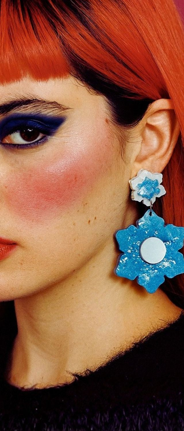 Portrait serré d’une femme audacieuse avec une boucle d’oreille fleur bleue XXL. Bijou statement fait main à Marseille par Kiss Me Zombie.