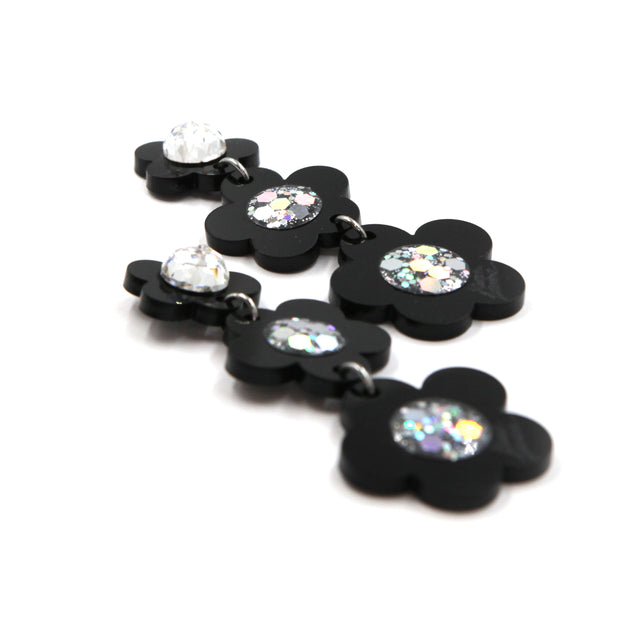 other side view of Black laser cut acrylic flowers earrings with glitter center on a white background