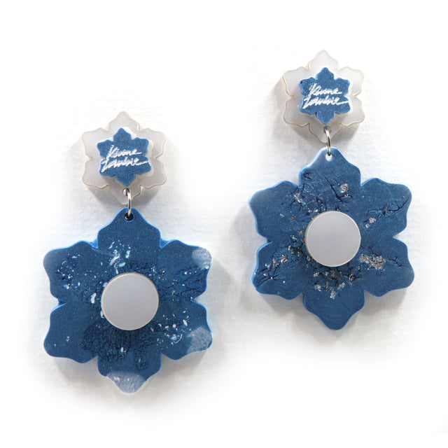 close up of blue and white marbled resin flower statement clip on earrings on a white background