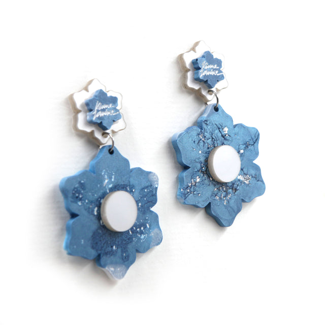 other side view closer of blue and white marbled resin flower statement clip on earrings on a white background