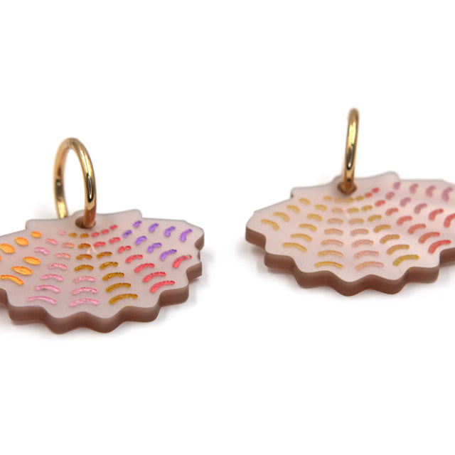 vue de côté de créoles épaisses en acier inoxydable dorées à l'or fin et breloques coquille saint jacques en acrylique nacré rose et détails gravé sur fond blanc