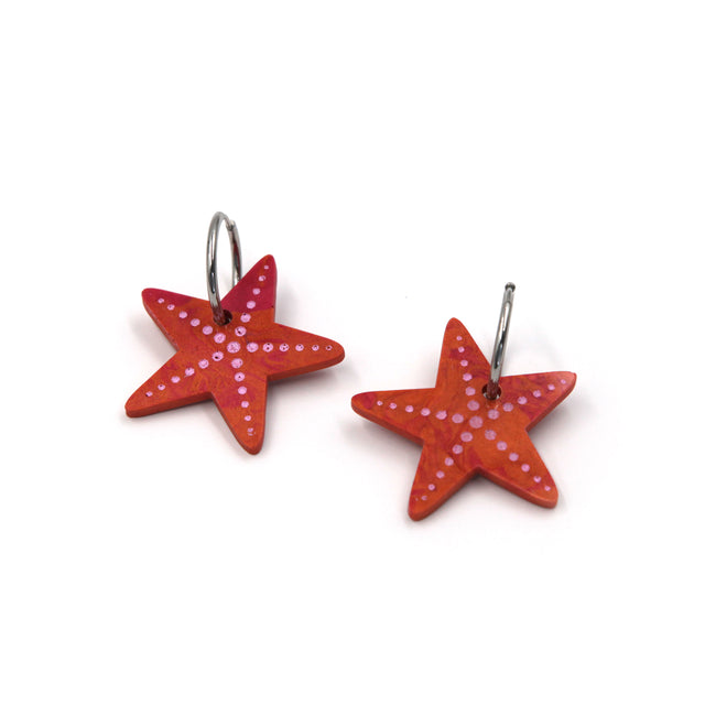 vue de côté de boucles d'oreilles créoles étoile de mer en résine orange corail et détails peint