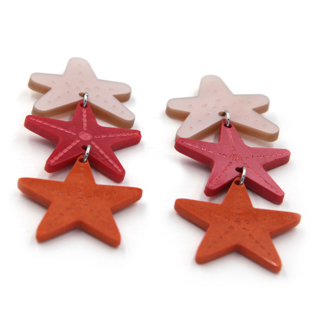 zoom vue de côté de boucles d'oreilles en résine et acrylique découpé au laser composés de trois étoiles de mer sur fond blanc