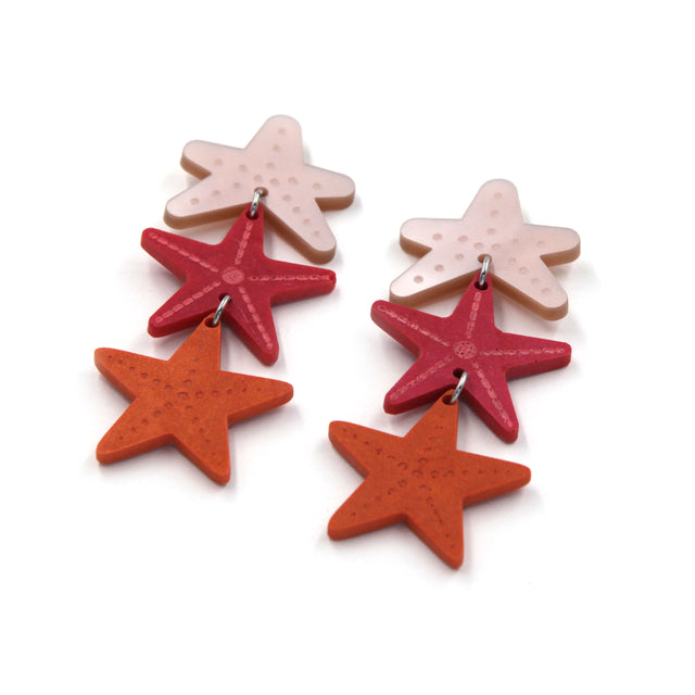 détails de boucles d'oreilles en résine et acrylique découpé au laser composés de trois étoiles de mer sur fond blanc