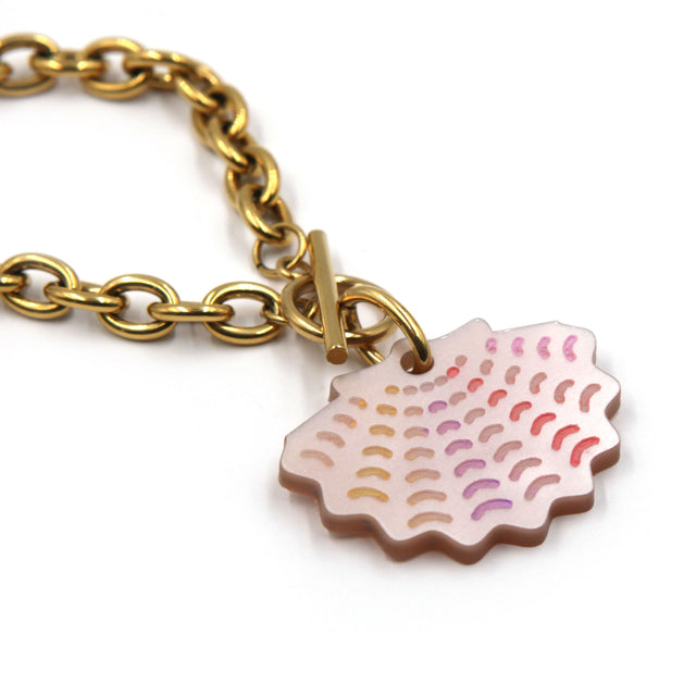 zoom sur collier grosse chaine forçat en acier inoxydable doré à l'or fin, avec un fermoir en T où se trouve une breloque coquille saint jacques en acrylique rose nacré et détails peints à la main sur fond blanc