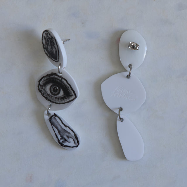 Verso des boucles d’oreilles DRAMARAMA cœur, œil et main en acrylique blanc avec clous en acier inoxydable
