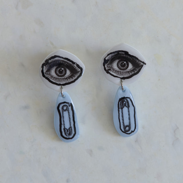 Boucles d’oreilles DRAMARAMA avec œil noir et blanc et épingle à nourrice sur acrylique bleu pâle
