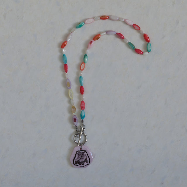 Vue entière du collier DRAMARAMA en perles de nacre multicolores avec pendentif patins à roulettes