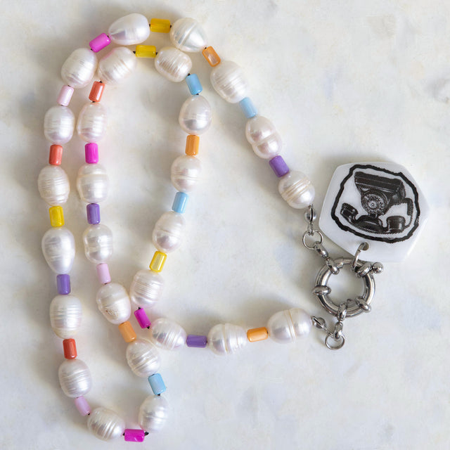 Gros plan sur le pendentif téléphone en acrylique et les perles d’eau douce du collier DRAMARAMA