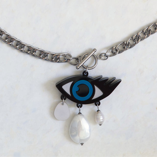 Gros plan sur le pendentif mauvais œil en acrylique noir, bleu et blanc avec perles