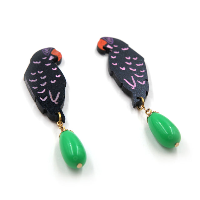 colose up side view of laser cut parrot statement earrings, hand painted with green vintage beads on a white background