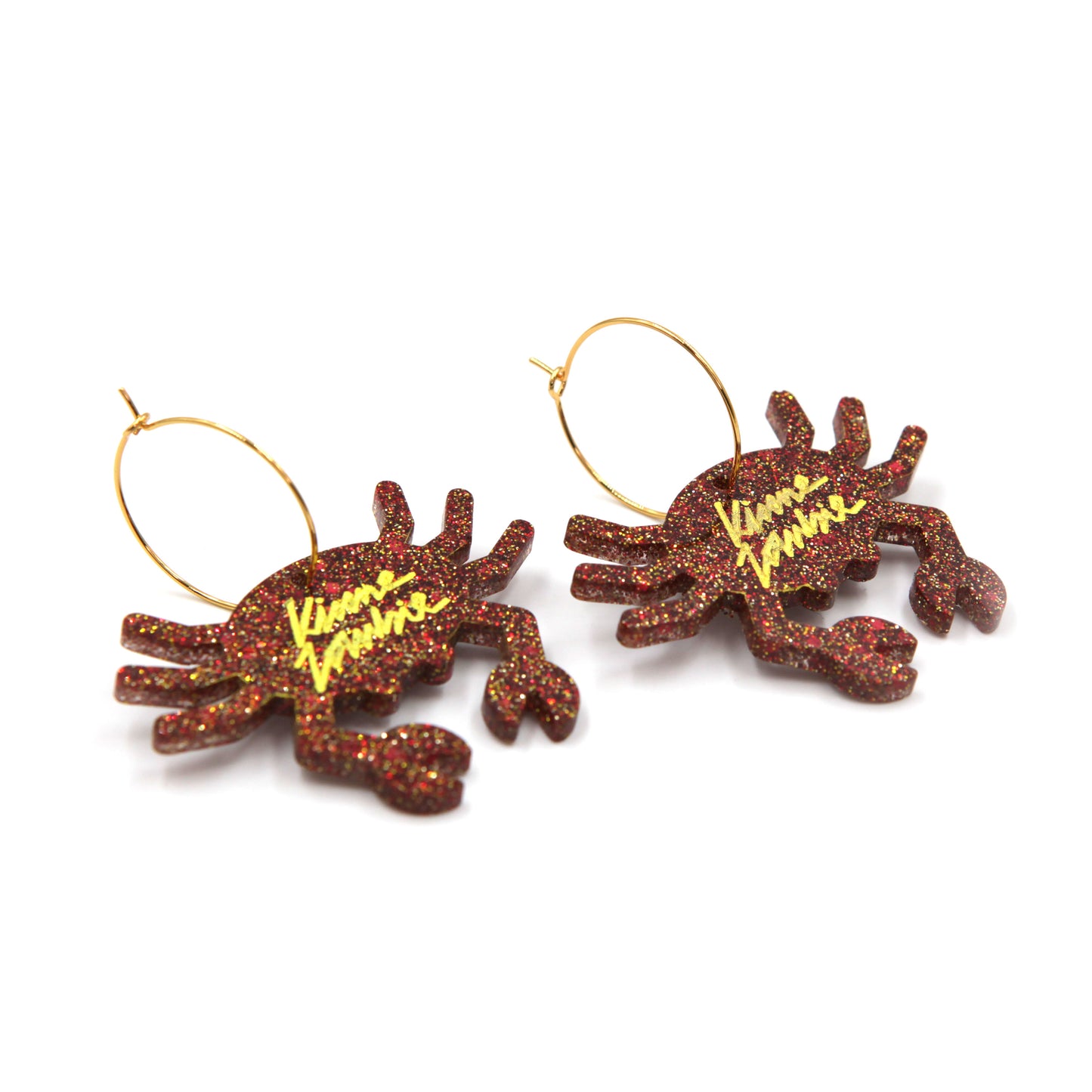 side view of Orange glitter resin crab gold plated hoop earrings on a white background