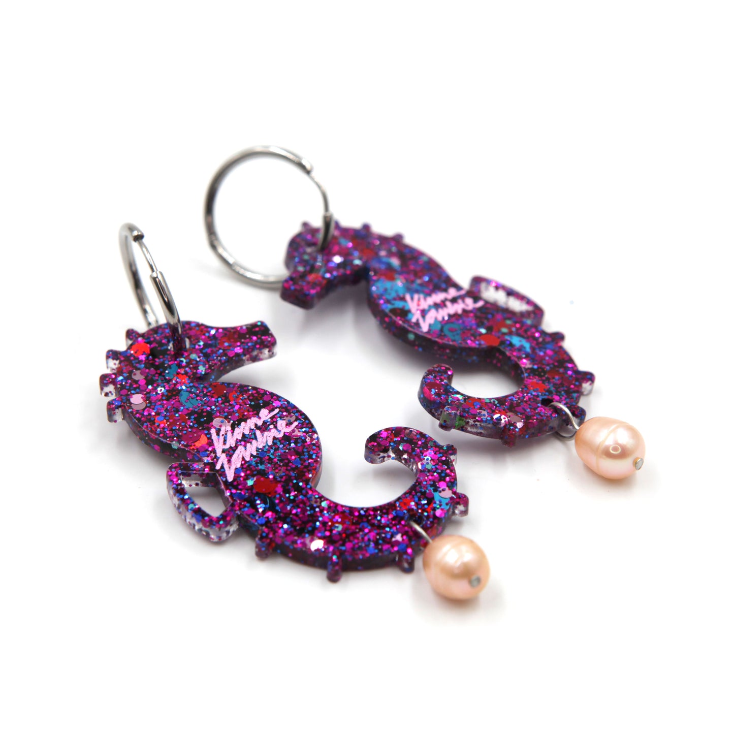side view of pink glitter resin sea horse hoop earrings with freshwater pearls on a white background