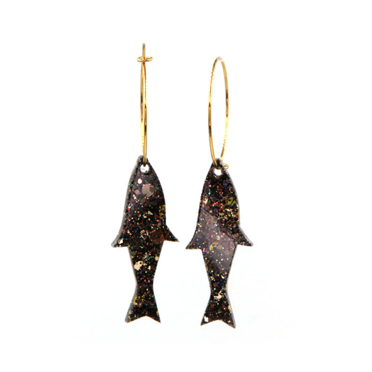 close up of gold glitter fish gold plated hoop earrings on a white background