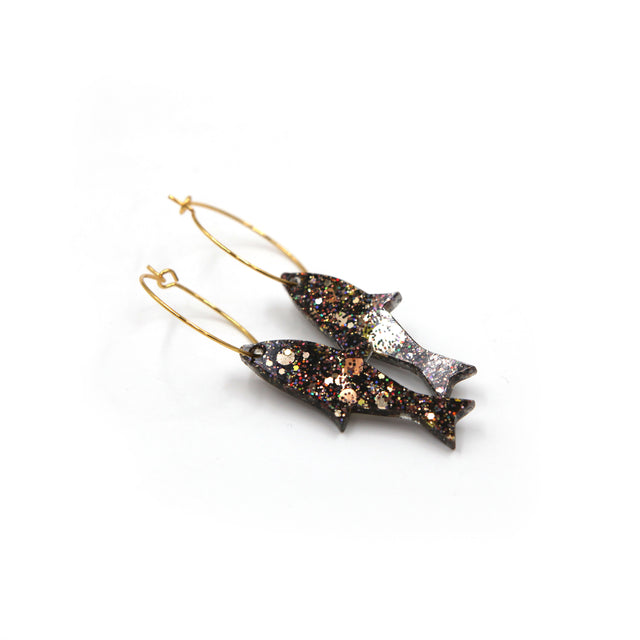 side view of gold glitter fish gold plated hoop earrings on a white background