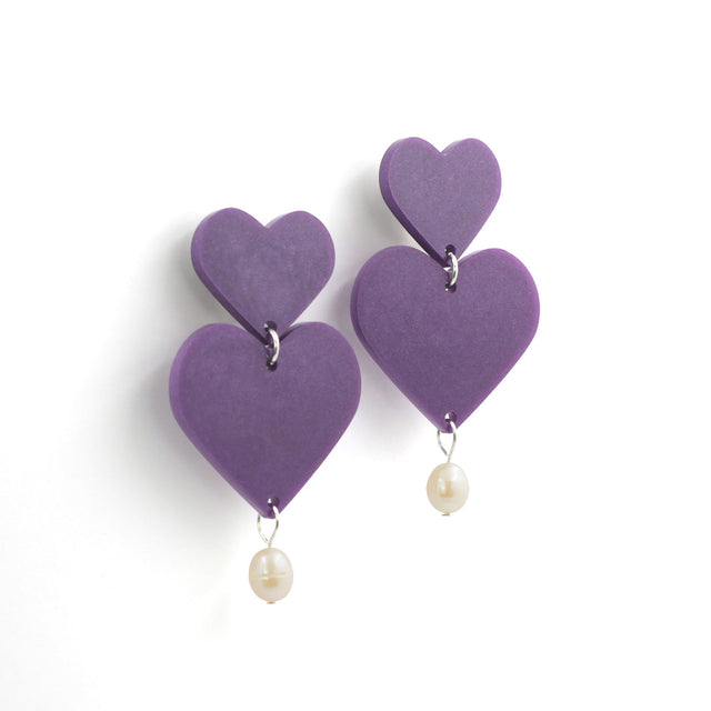 This is a picture of purple hearts earrings with freshwater pearls on a white background. 