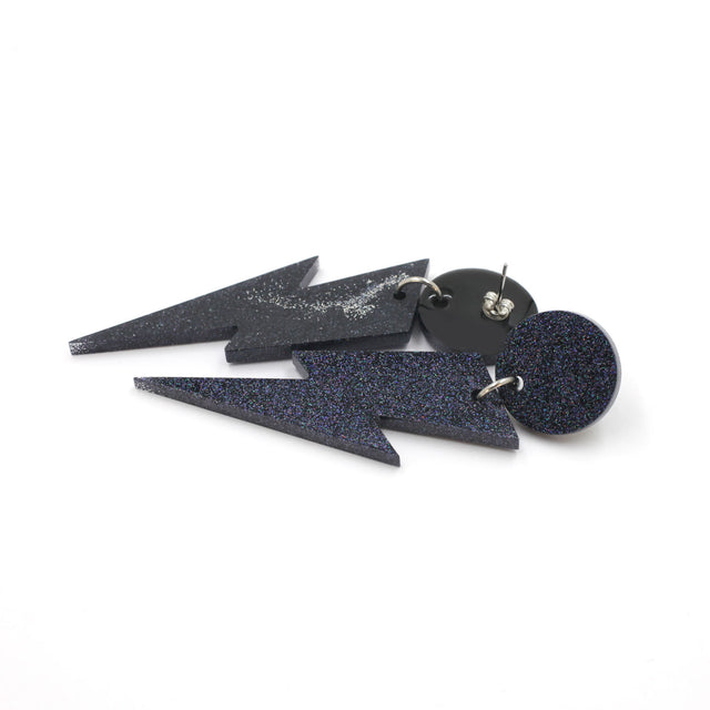 this is a picture of black holographic glitter bolt and dot dangle earrings on a white background. one is on the back, the stud are silver on a black dot.