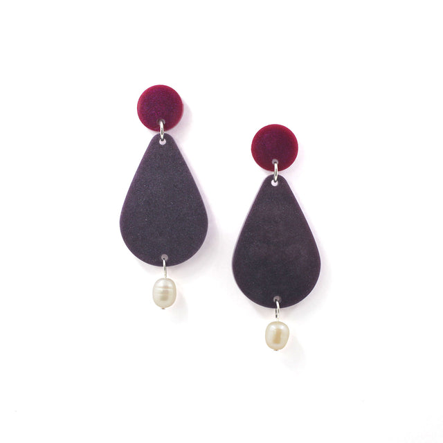 picture of earrings on a white background. the earrings are composed by a pink dot at the top, then a bigger purple pear shape and a freshwater pearls at the bottom hanging.