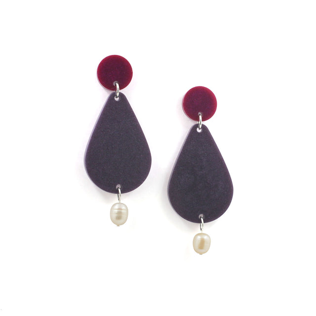 picture of earrings on a white background. the earrings are composed by a pink dot at the top, then a bigger purple pear shape and a freshwater pearls at the bottom hanging.