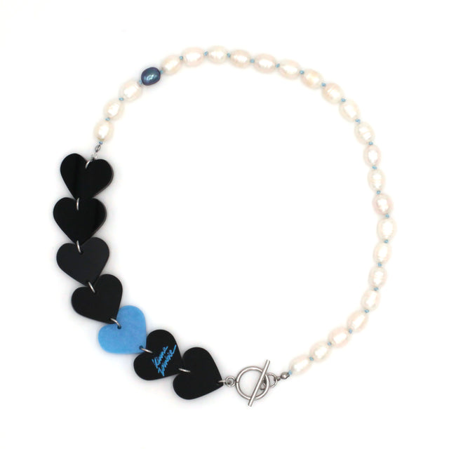 Laser-cut and resin black and blue hearts necklace with freshwater pearls and toggle clasp on a white background.