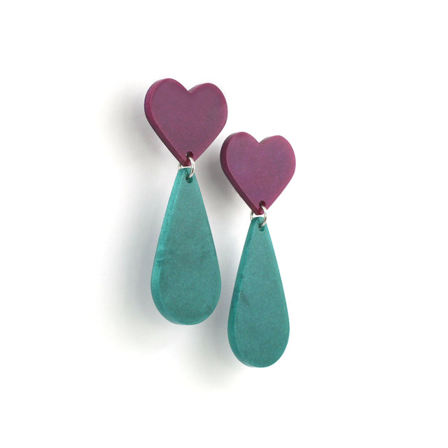 This is a picture of dangles earrings on a white background. The top of the earrings are purple heart and the pendants are green teardrop. 