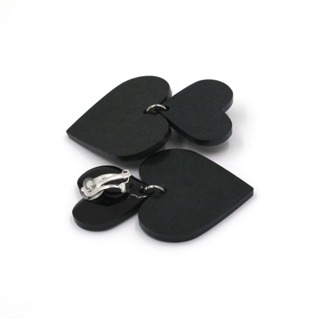 black hearts earrings on a white background. one is on its back, there is a clip on earring with a silicone pad protection.