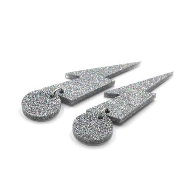 this is a picture of silver holographic glitter bolt and dot dangle earrings on a white background.