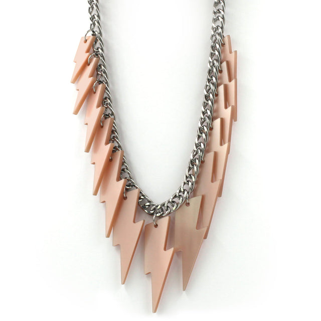 close up of a necklace hanging on a white back ground, composed of a chunky silver tone curb chain with 13 pieces of pink pearly lightning bolts of graduant size.