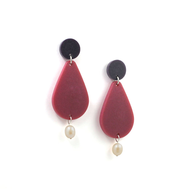 picture of earrings on a white background. the earrings are composed by a purple dot at the top, then a bigger dark pink pear shape and a freshwater pearls at the bottom hanging.