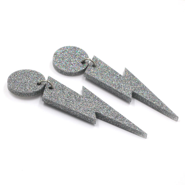this is a picture of silver holographic glitter bolt and dot dangle earrings on a white background.