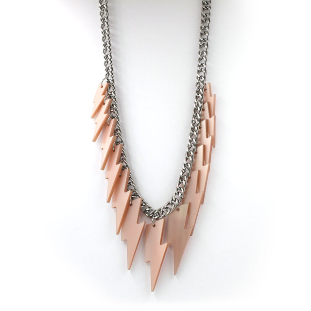 This is a necklace hanging on a white back ground, composed of a chunky silver tone curb chain with 13 pieces of pink pearly lightning bolts of graduant size.