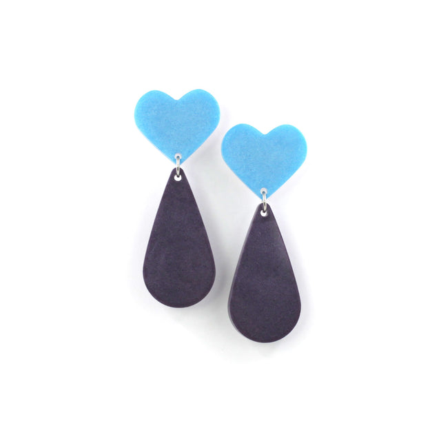 This is a picture of dangles earrings on a white background. The top of the earrings are blue heart and the pendants are purple teardrop. 