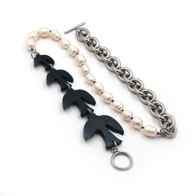 this is necklace composed by laser cut black birds, pearls and chunky chain on a white background.