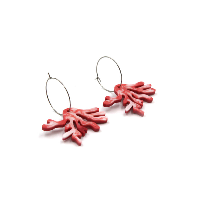 side view of white and light red resin coral hoops earrings on a white background