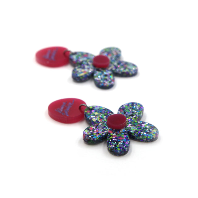 side view of blue resin confetti flowers with round pink laser-cut clip-on earrings on a white background