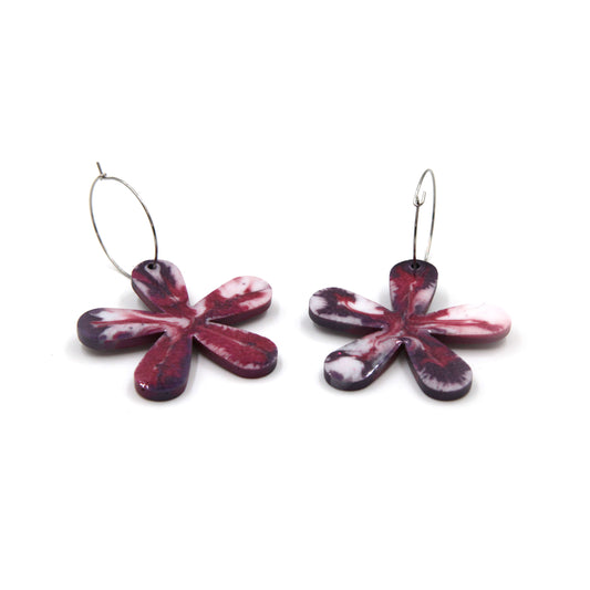 side view of berry pink, purple and white marbled resin statement flower hoop earrings on a white background