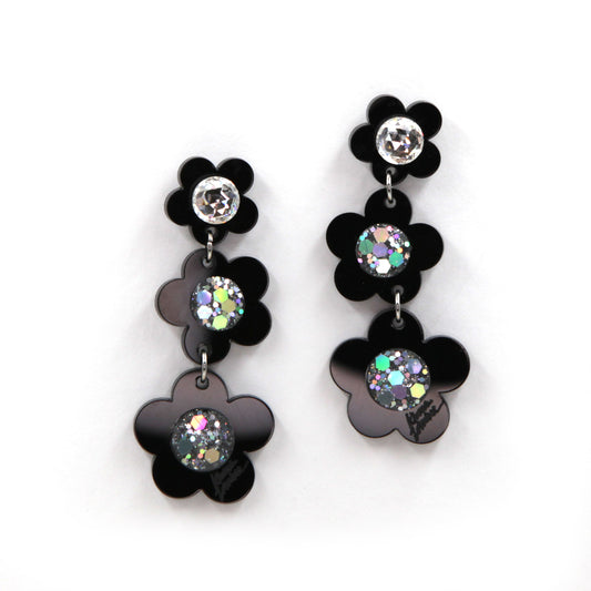 Black laser cut acrylic flowers earrings with glitter center on a white background