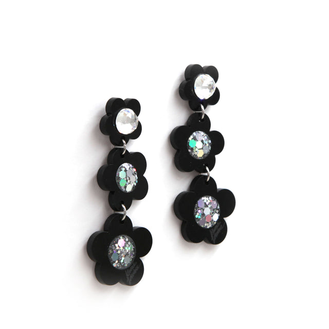 other side view of Black laser cut acrylic flowers earrings with glitter center on a white background