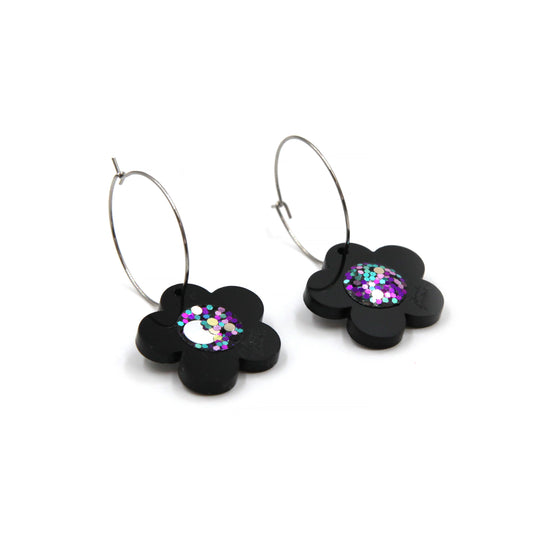 side view of black laser cut acrylic flower with a pink glittery resin center hoop earrings
