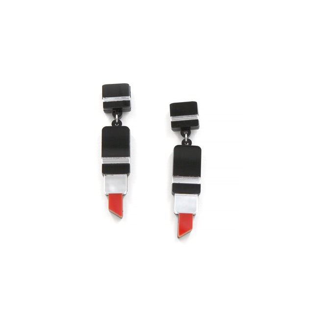 vue plus éloignée des boucles d'oreilles en forme de tube de rouge à lèvre en acrylique noir, rouge et miroir argenté découpé au laser sur fond blanc