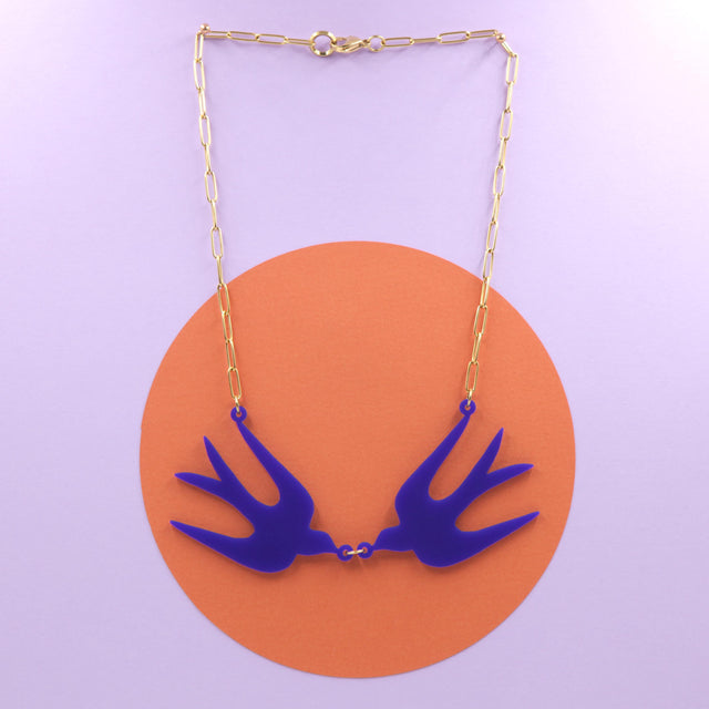 Collier plastron avec deux oiseaux bleu Klein, inspiré des découpes de Matisse, monté sur une chaîne trombone dorée. 