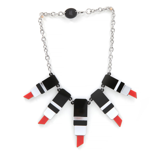 un collier plastron tube de rouge à levre en acrylique découpé au laser, noir, rouge et miroir argenté avec une grosse chaine forçat en acier inoxydable sur fond blanc