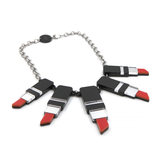 autre vue de côté un collier plastron tube de rouge à levre en acrylique découpé au laser, noir, rouge et miroir argenté avec une grosse chaine forçat en acier inoxydable sur fond blanc