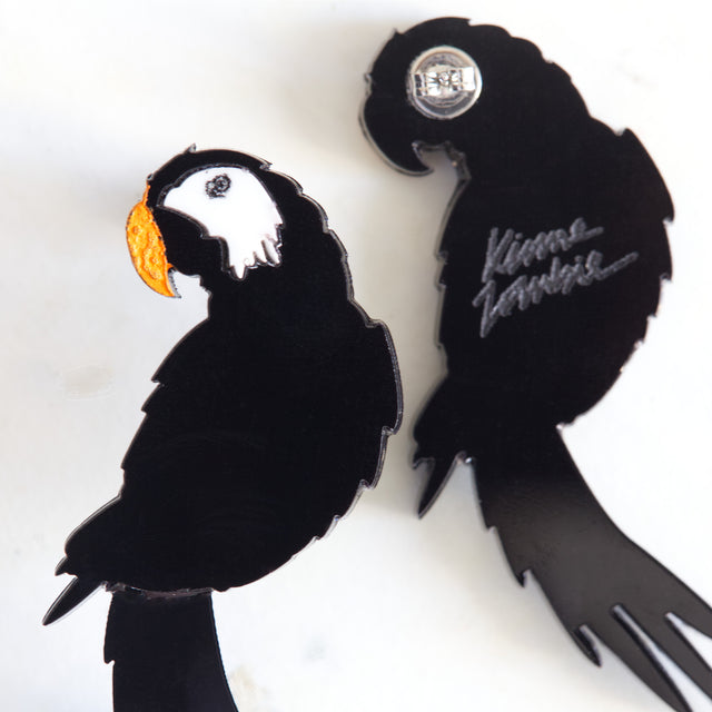 Gros plan sur les boucles d’oreilles perroquet Disco Parrot en acrylique noir, blanc et orange