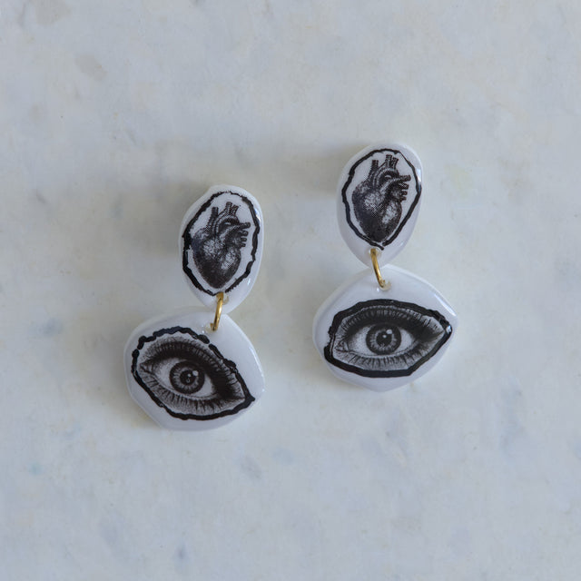 Boucles d’oreilles DRAMARAMA avec cœur anatomique et œil noir et blanc sur acrylique blanc