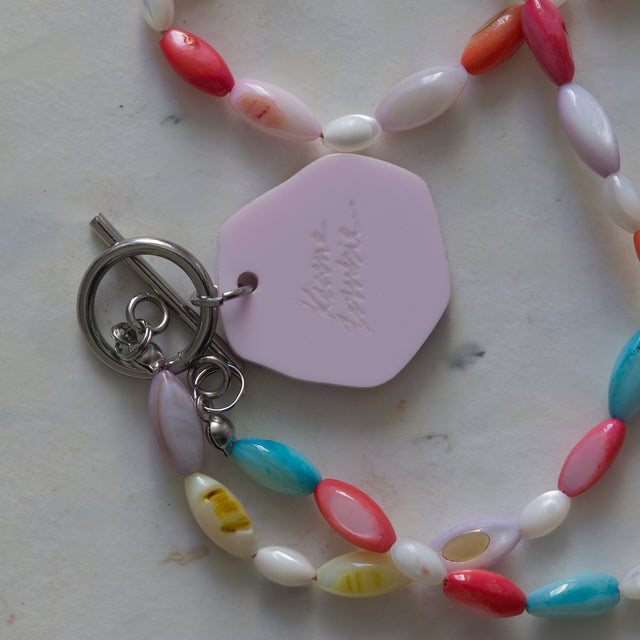 Gros plan sur le fermoir en T, le dos du pendentif rose et les perles de nacre colorée