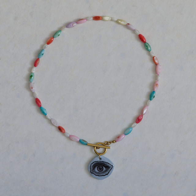 Collier DRAMARAMA en nacre colorée et blanche avec pendentif œil bleu et fermoir doré