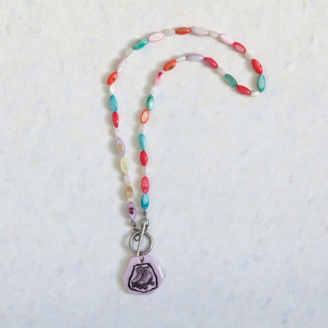 Vue entière du collier DRAMARAMA en perles de nacre multicolores avec pendentif patins à roulettes