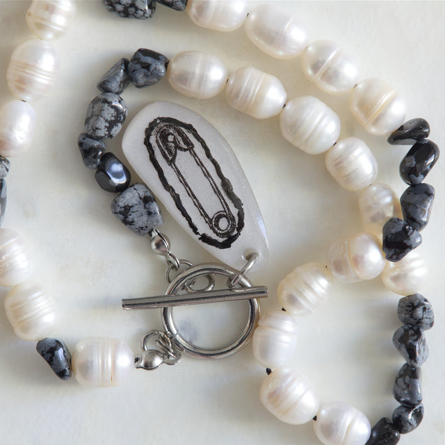 Gros plan sur le pendentif épingle, les perles d’eau douce et les nuggets d’obsidienne du collier DRAMARAMA